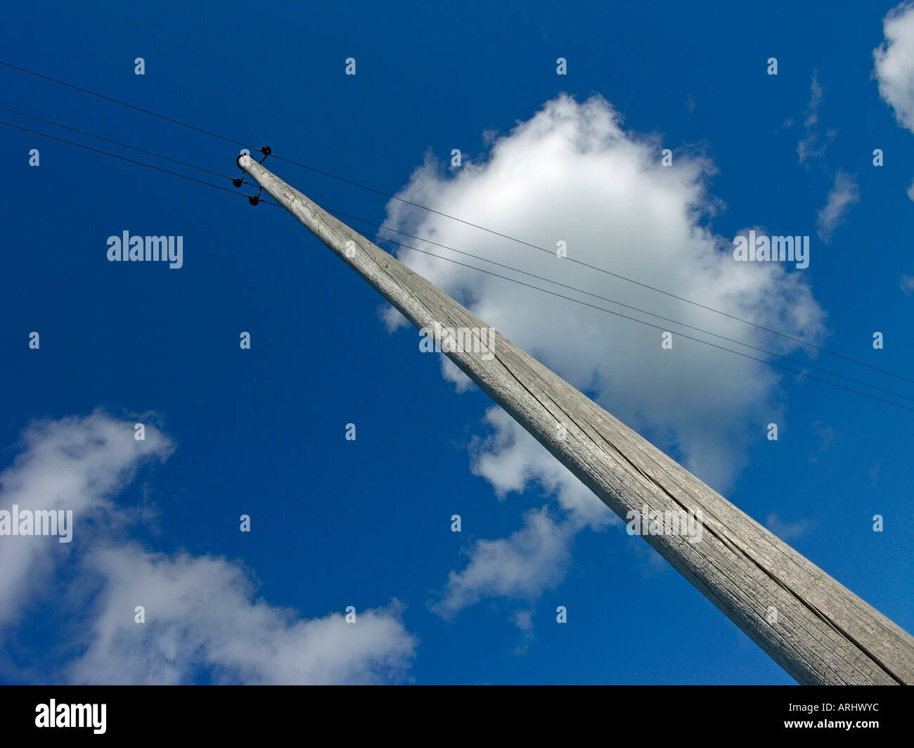 old telephone mast with antiquated cables against blue sky with clouds Stock Photo