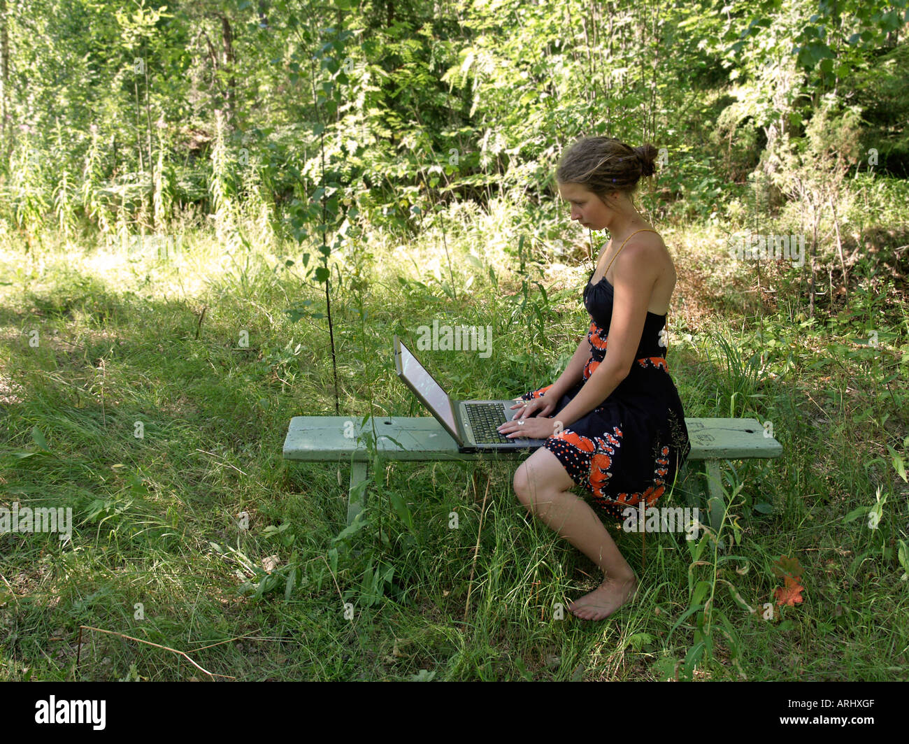 young woman girl in the nature sitting on a bench working with a notebook Stock Photo
