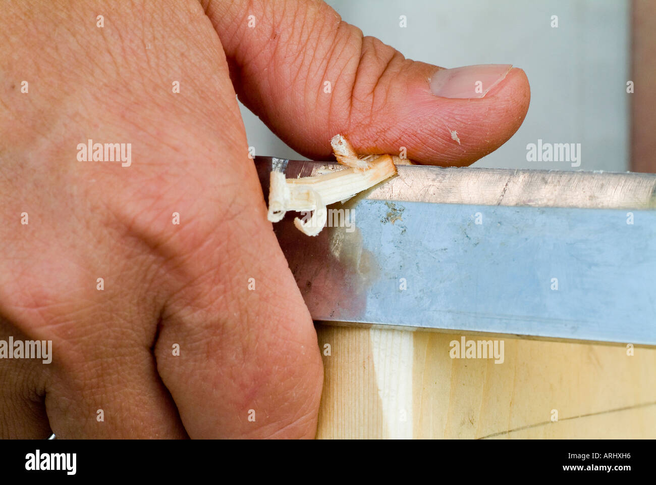 danger for accident dangerous action hand with a wounded hurt bloody thumb with a plaster by carving a piece of wood Stock Photo
