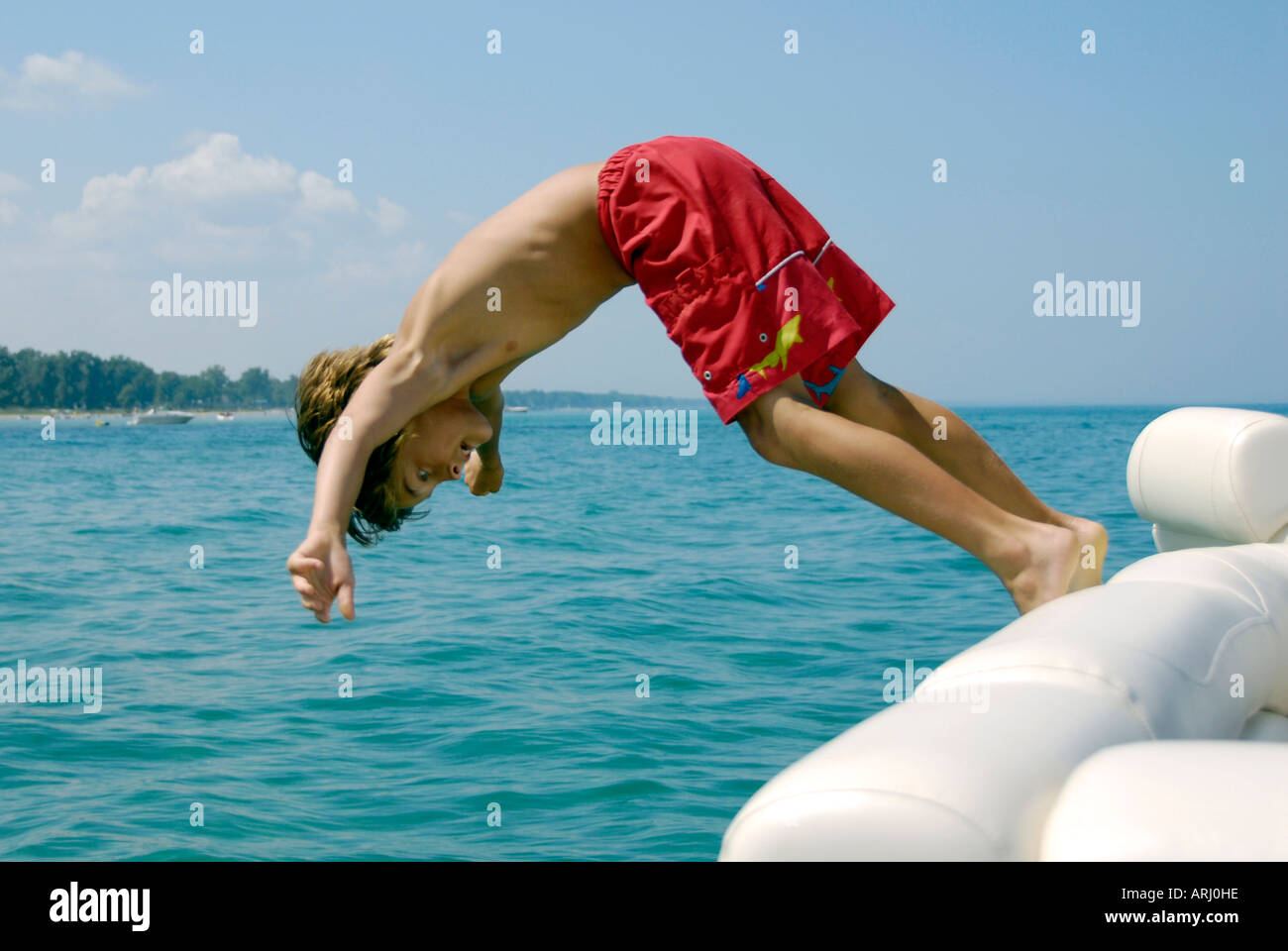 Boy dives into Lake Huron from a boat Stock Photo