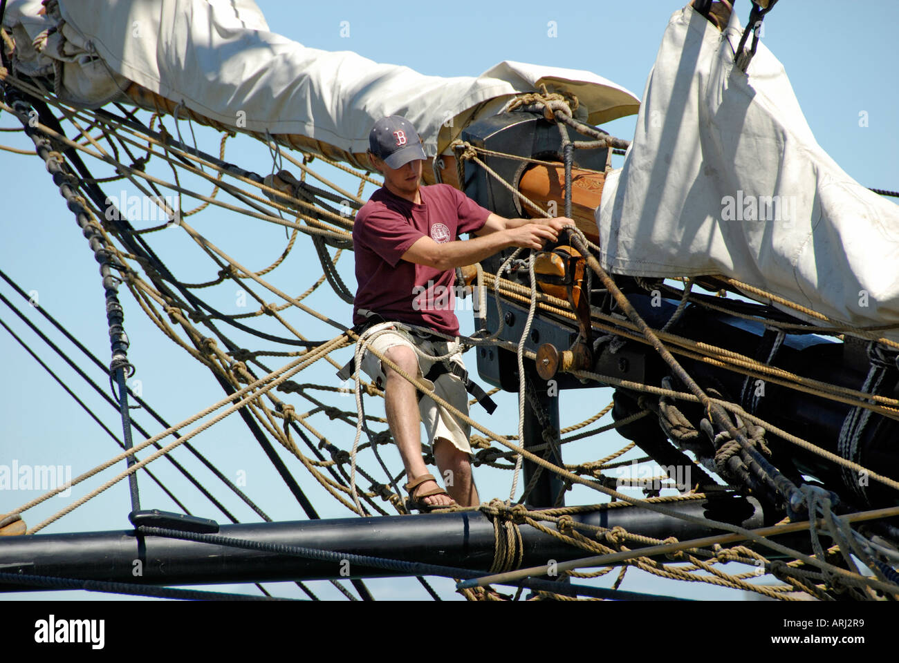 Sailors climb the mast of a tall sailing ship to effect maintenance and