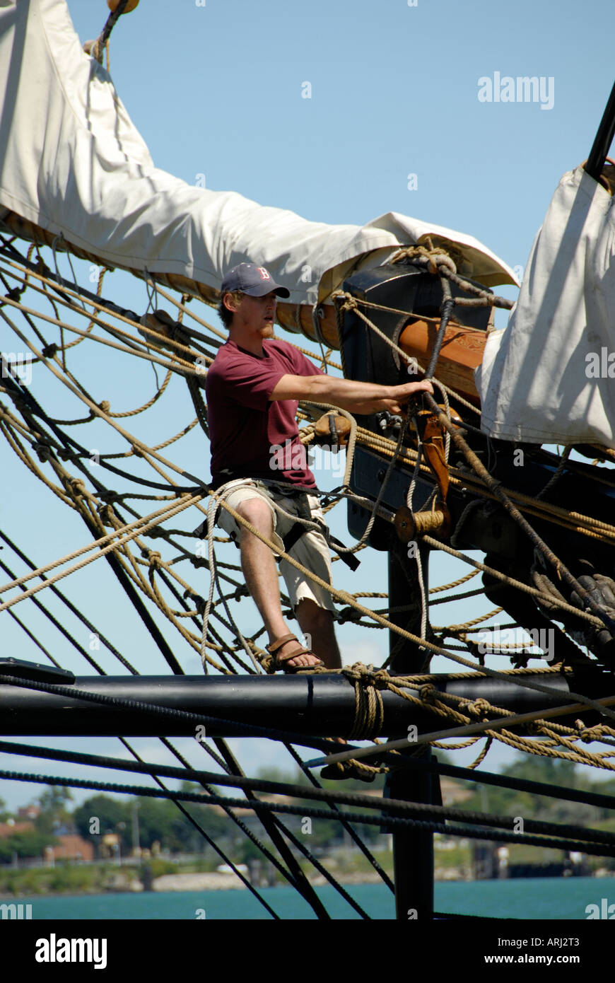 Sailors climb the mast of a tall sailing ship to effect maintenance and