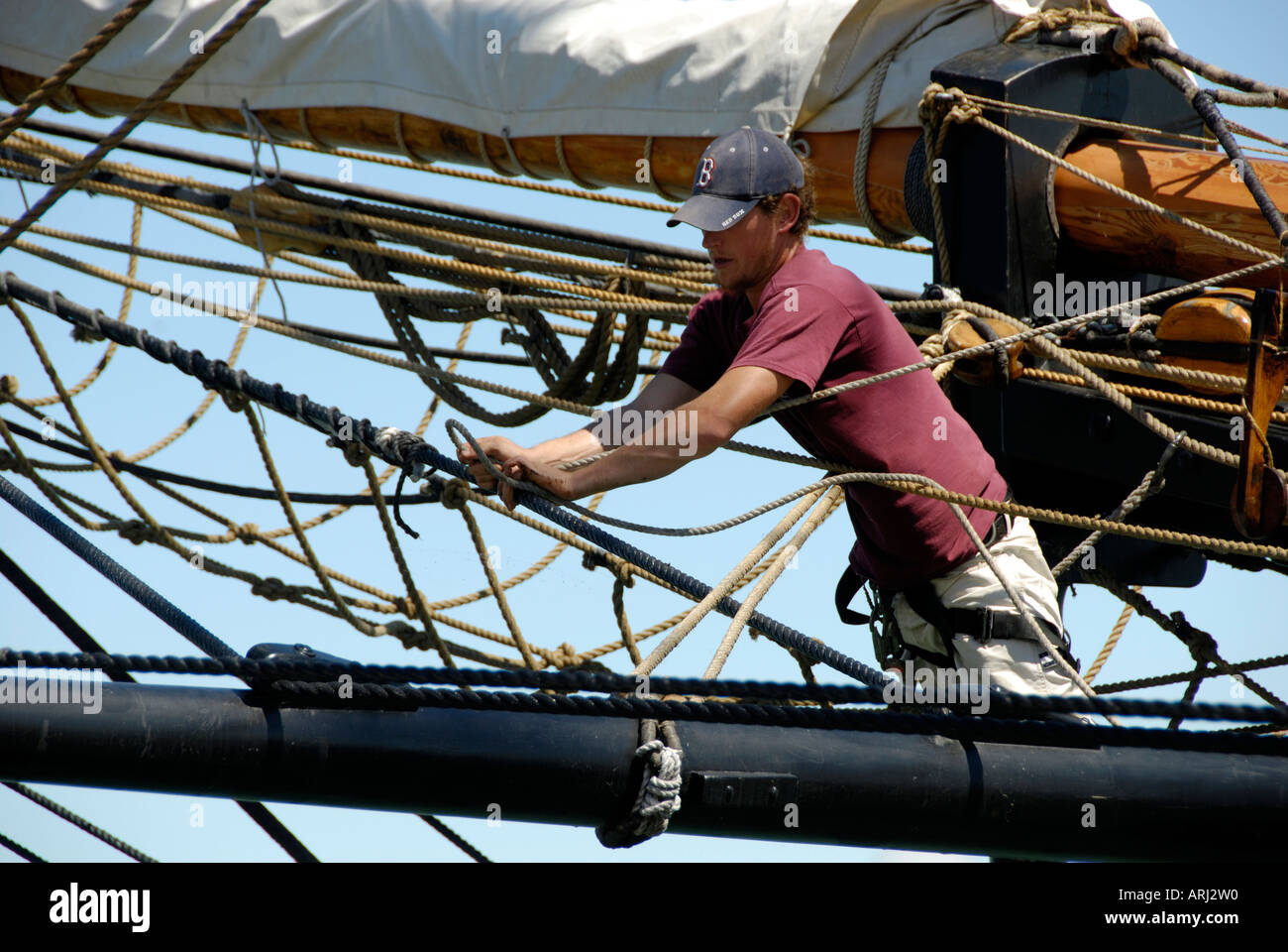Sailors climb the mast of a tall sailing ship to effect maintenance and