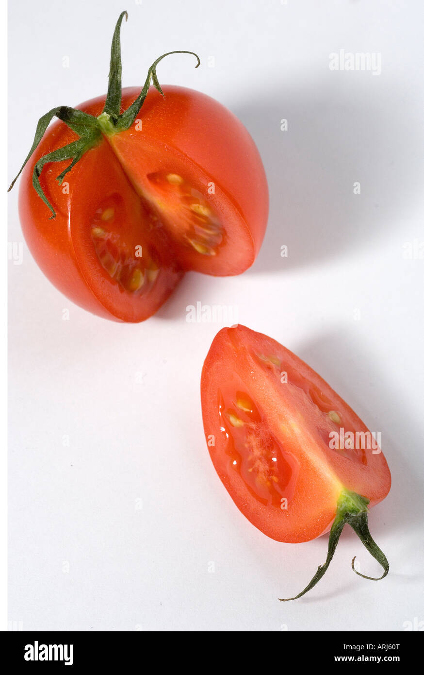 A red organic Tomato with its stalk on with Segment cut out against a white background Stock Photo