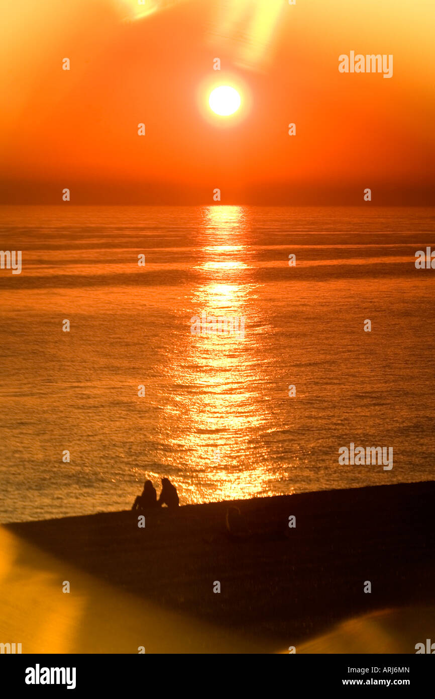 A couple watch the sunset over Brighton beach captured through the lens of a pair of sunglasses, Brighton, East Sussex, UK. Stock Photo