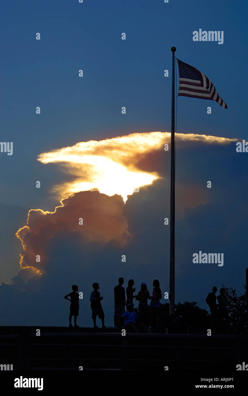 Sunset and clouds with people and the United State Flag Stock Photo