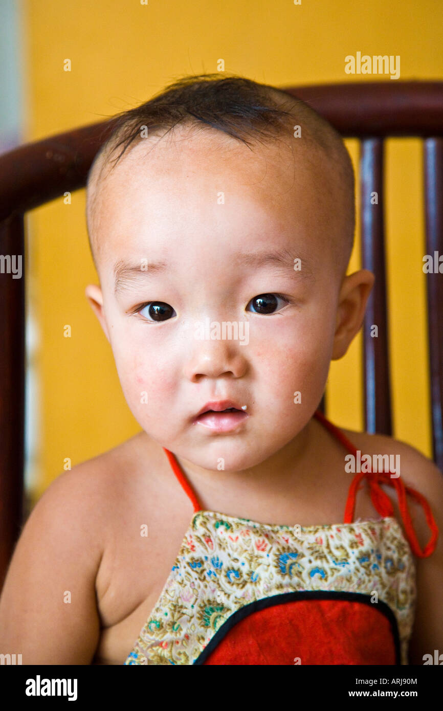 Close up young asian oriental peasant Chinese boy sitting looking to