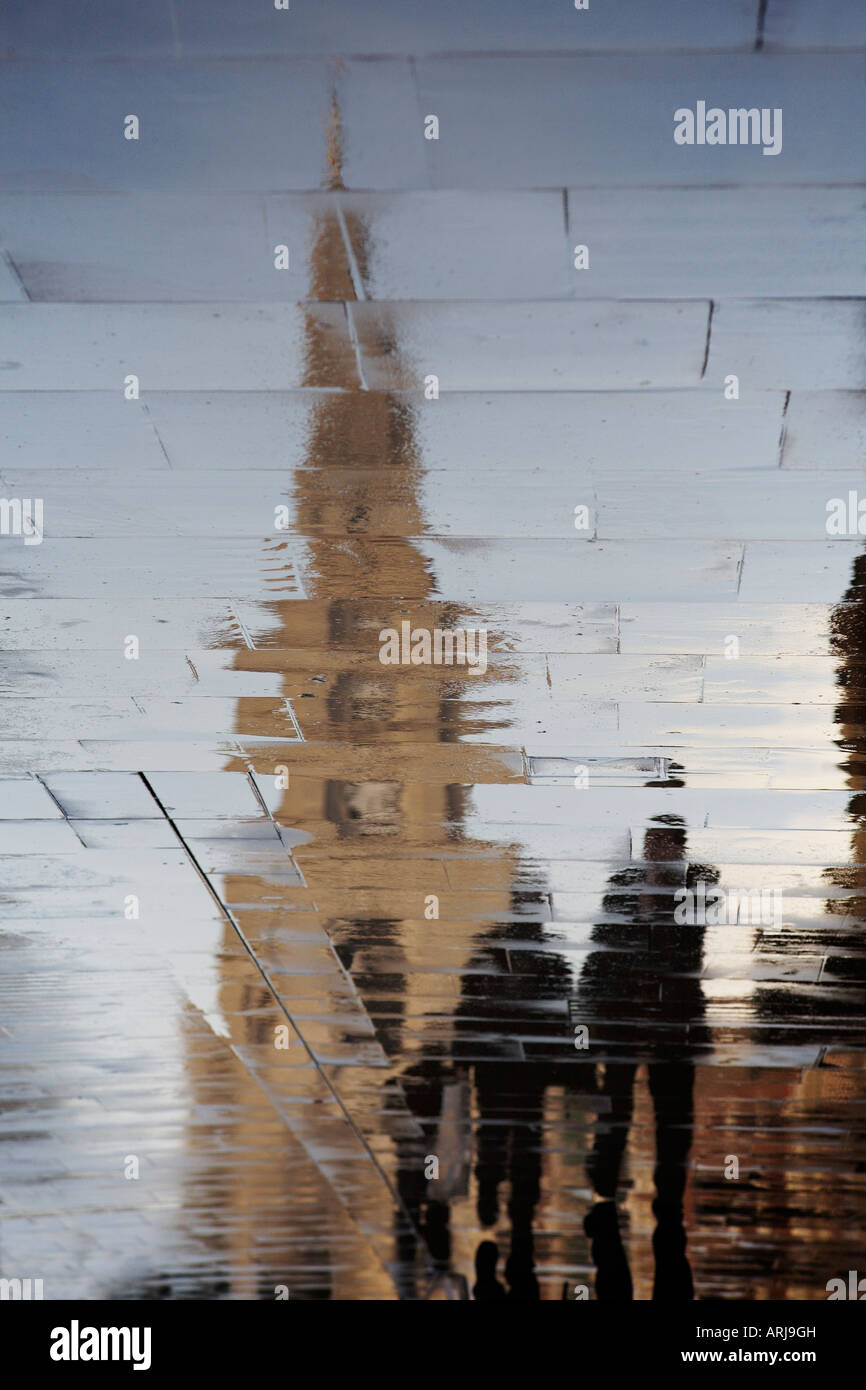Distorted reflection of Christchurch Spitalfields and pedestrians on wet pavement. Spitalfields, London, England Stock Photo