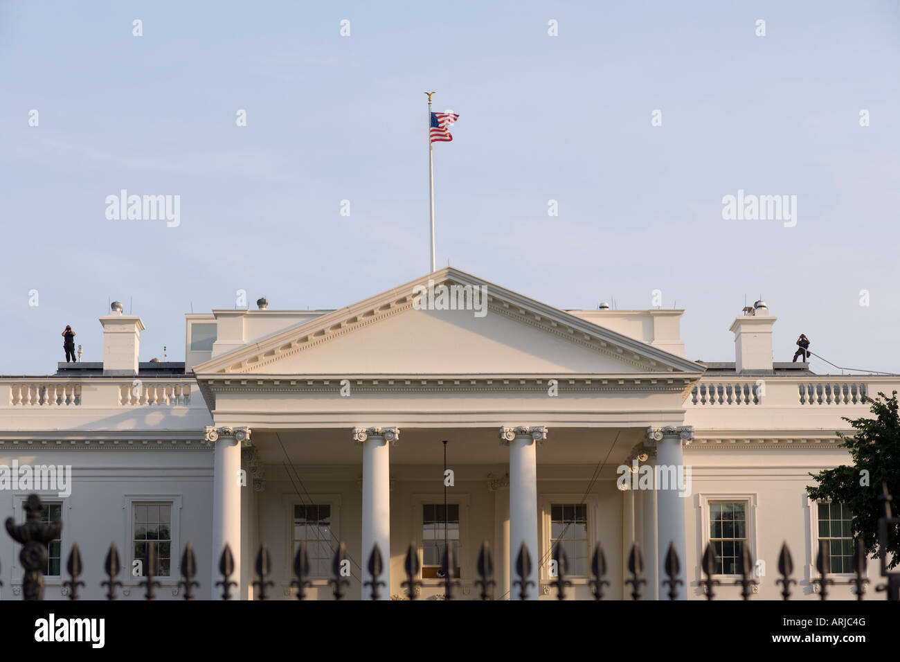 Two Secret Service agents looking back with binoculars from the roof of the White House Washington DC Stock Photo