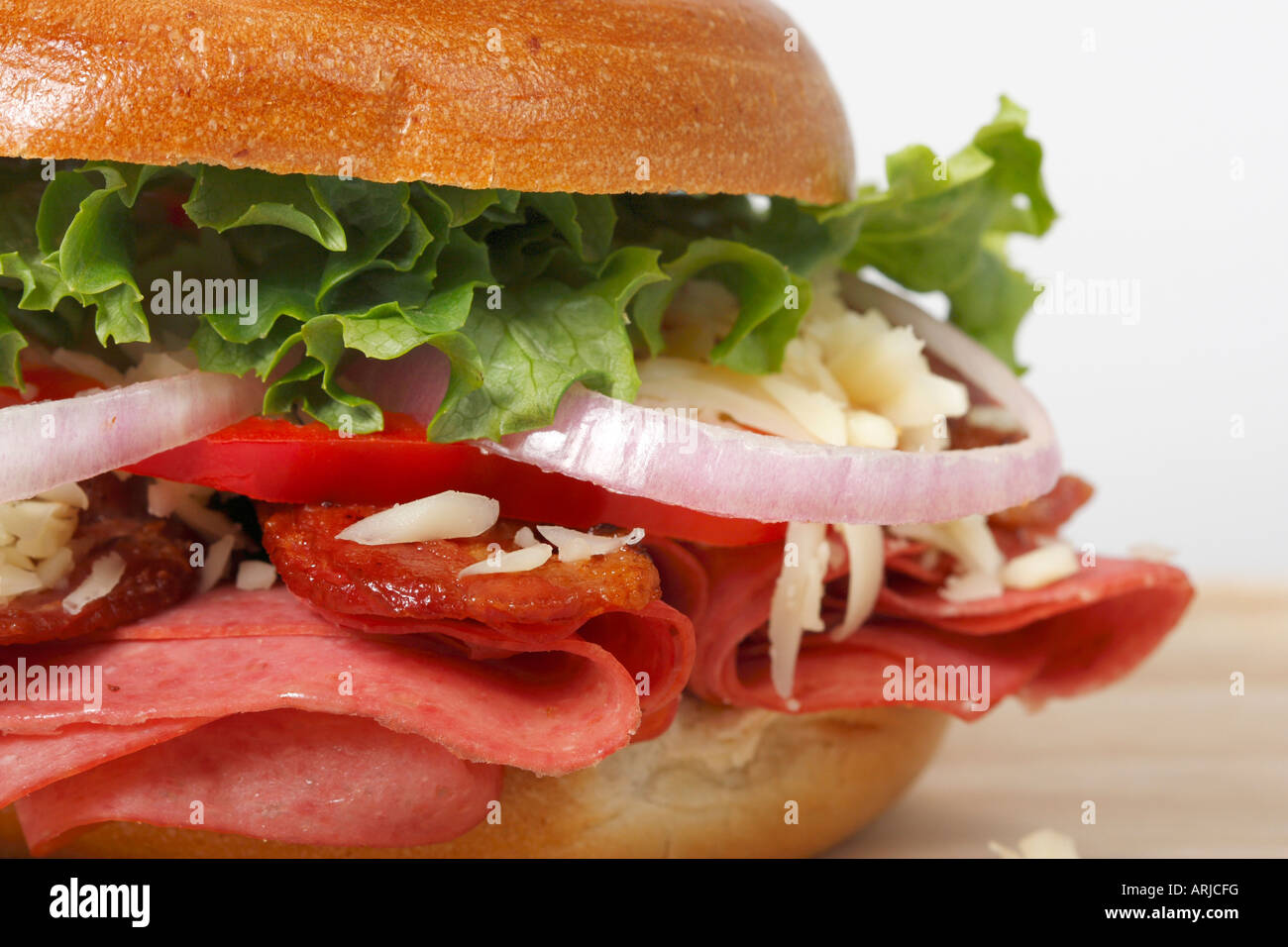 Closeup of one filled Bagel sandwich food on a wooden board vegetable garnish front view nobody closeup presentation horizontal in USA US hi-res Stock Photo