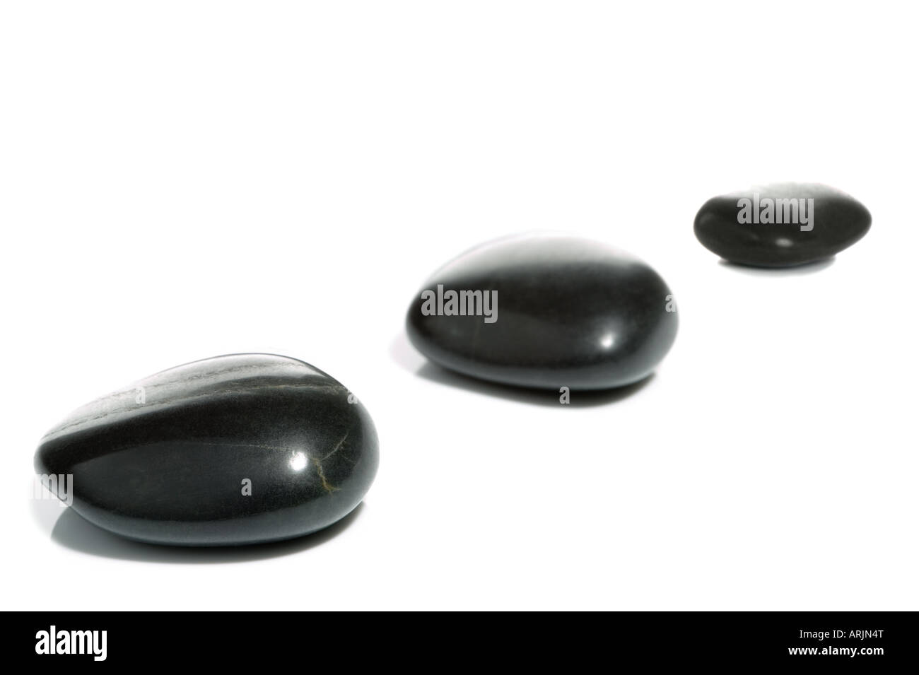 High key shot of three black pebbles on a white surface Stock Photo