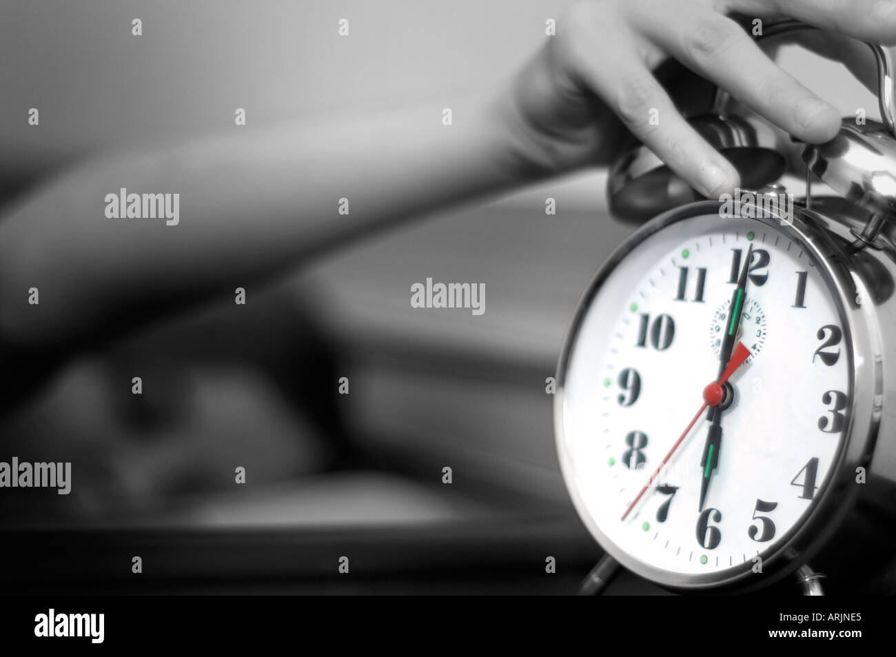Young Woman reaching for a Ringing Alarm clock showing just after 6 am with fresh and modern toning Stock Photo