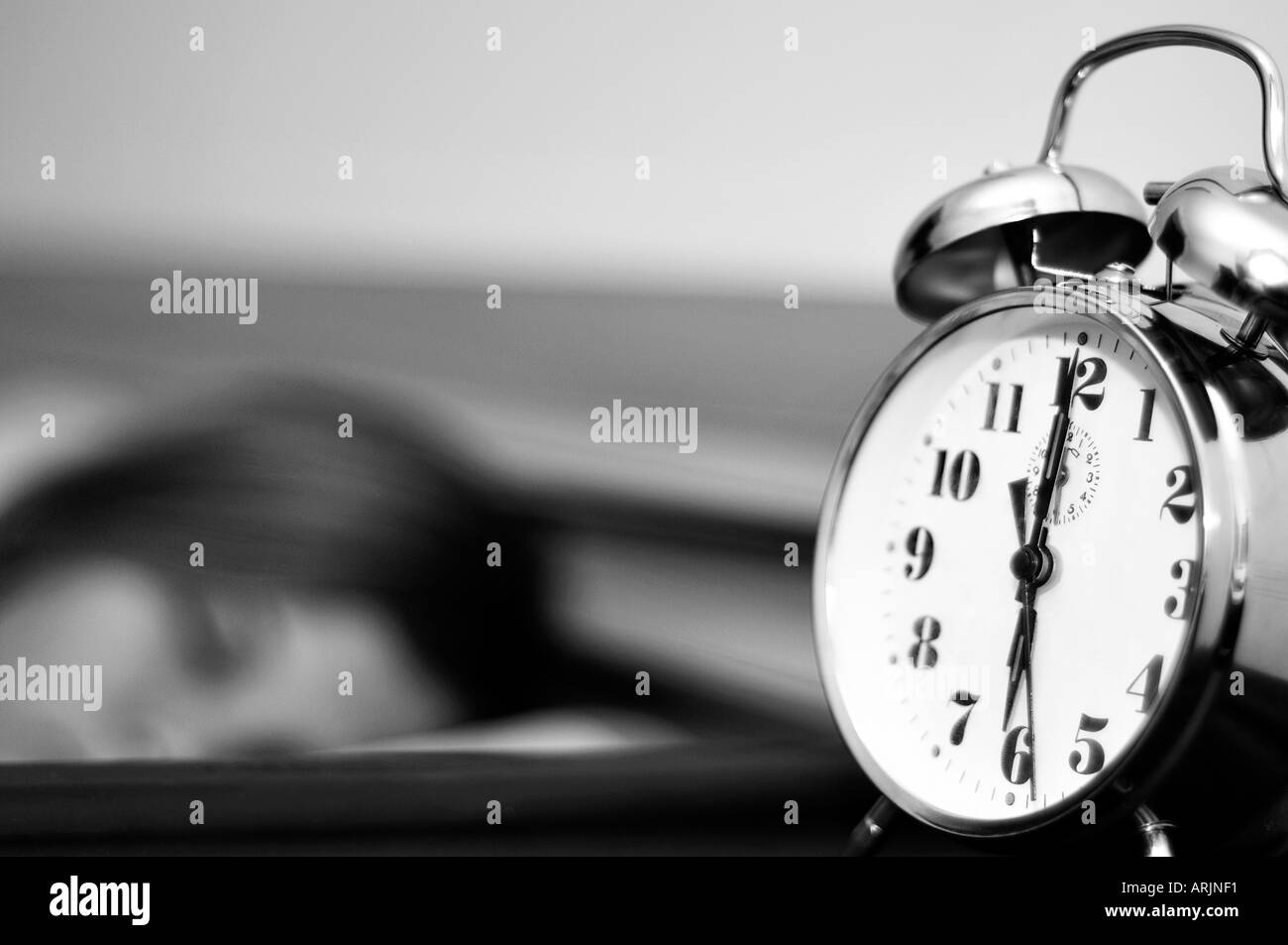 Sleeping young woman and a ringing alarm clock Stock Photo