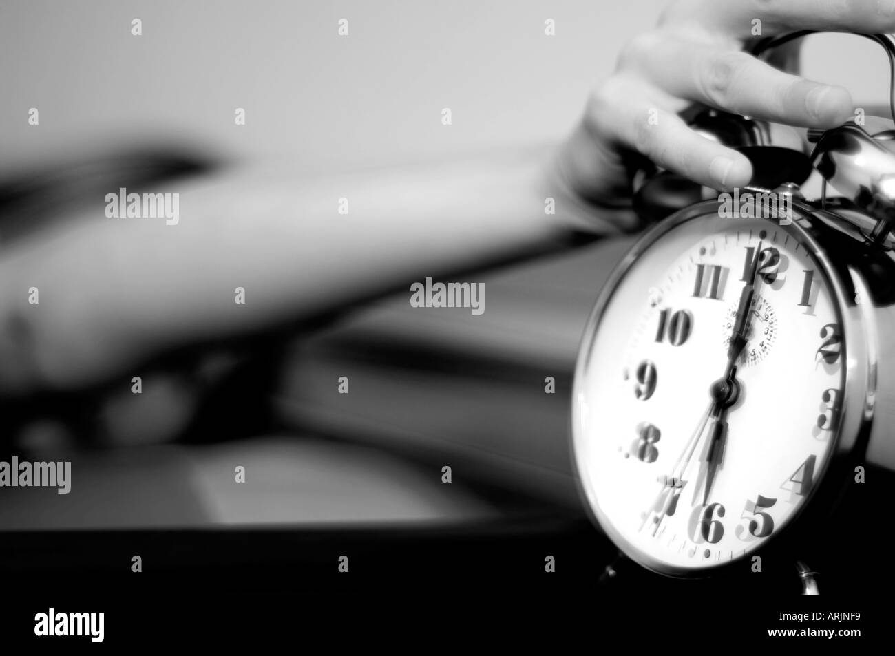 Sleeping young woman reaching for a ringing alarm clock Stock Photo