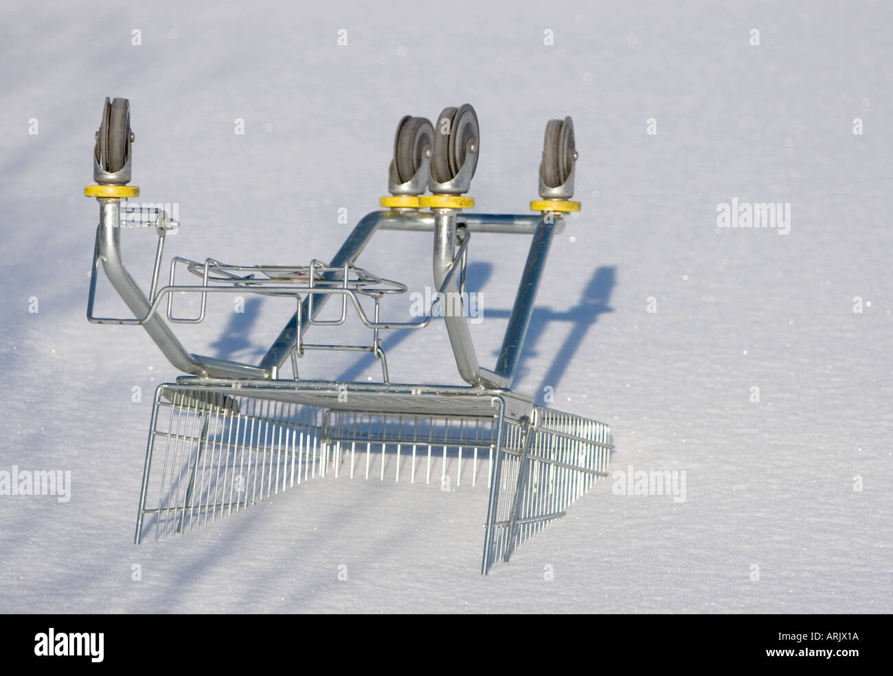 Shopping cart upside down outdoors and buried to snow , Finland Stock Photo