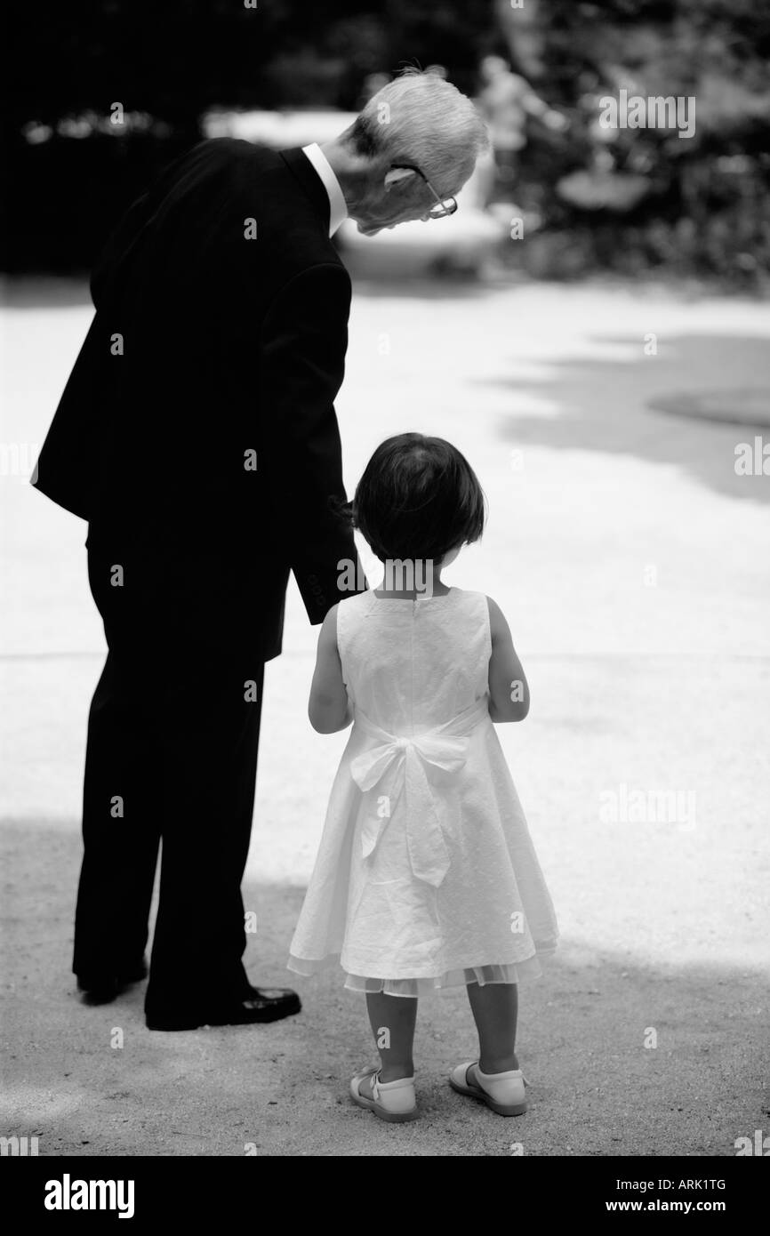 A grandfather tenderly talks to his granddaughter as he gives her his hand to reassure her Stock Photo