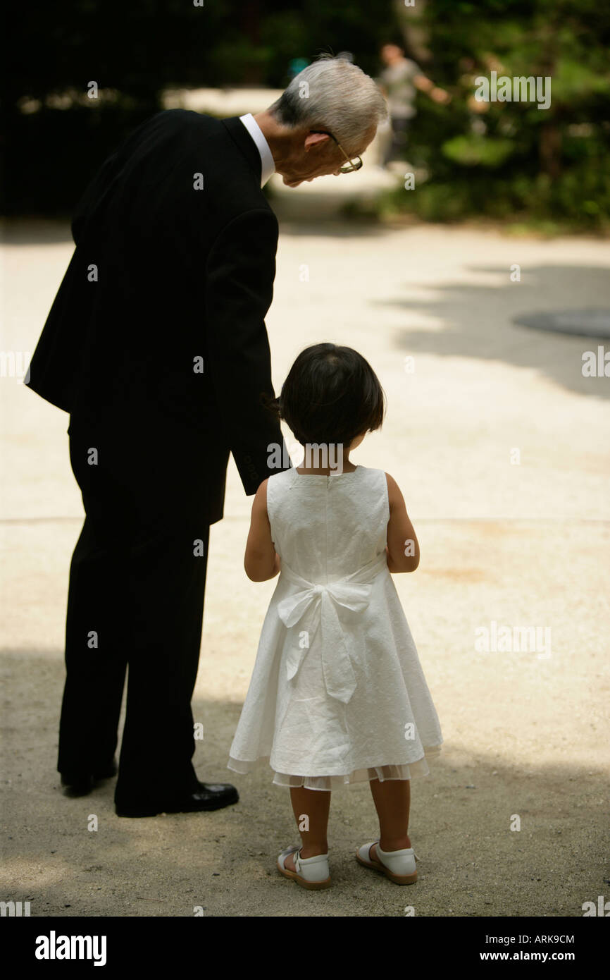 A grandfather tenderly talks to his granddaughter as he gives her his hand to reassure her Stock Photo