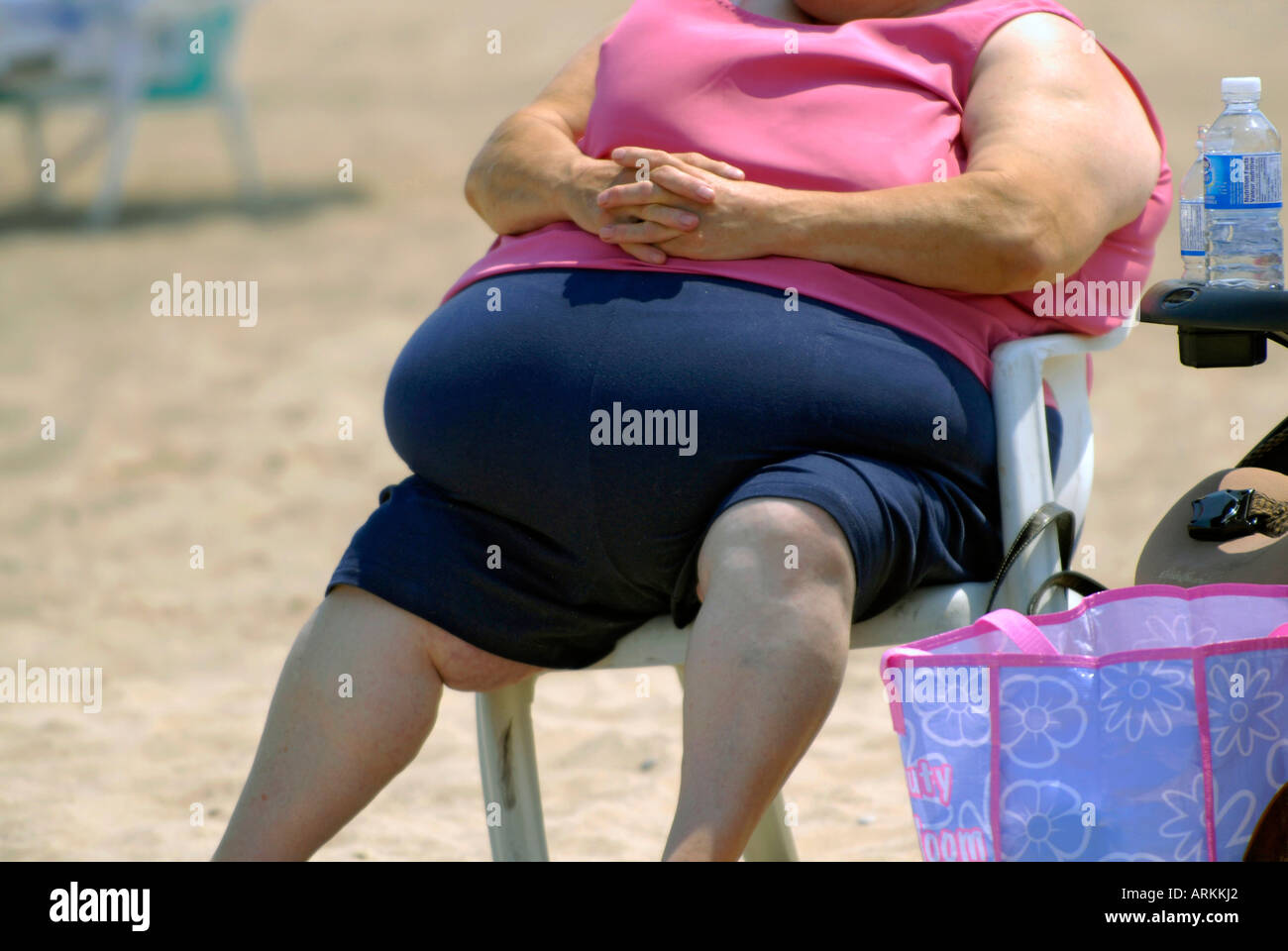 Very fat woman sitting in a chair on a beach Stock Photo