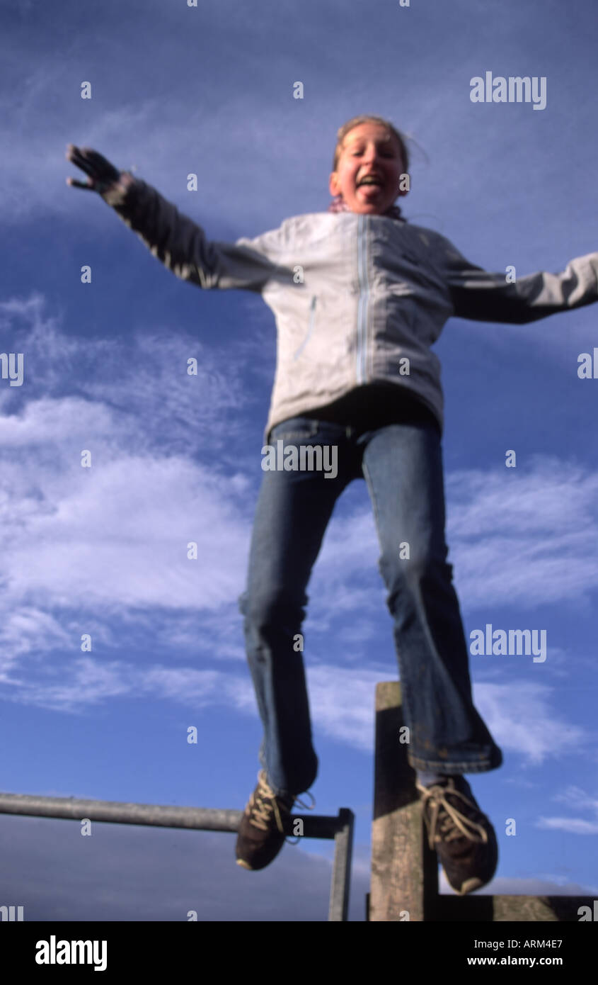 Eleven year old girl pulling a face as she jumps off a fence post Stock  Photo - Alamy