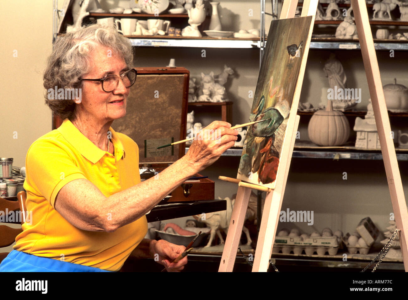 Retired elderly woman artisit enjoys creating an oil painting Stock