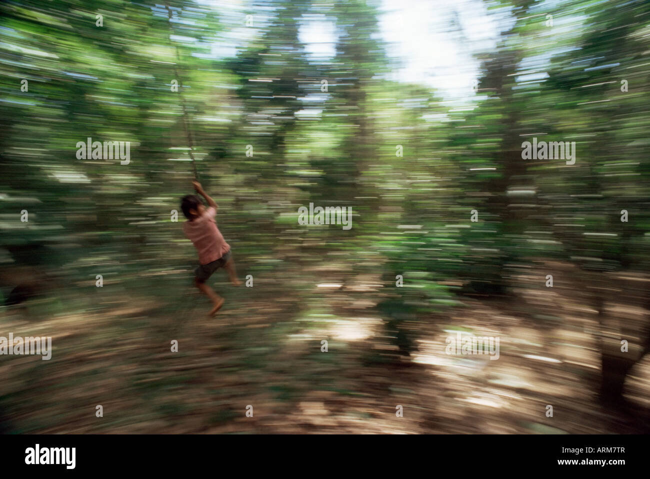 Local boy swings on vine, Corcovado National Park, Peninsula de Osa, Costa Rica, Central America Stock Photo