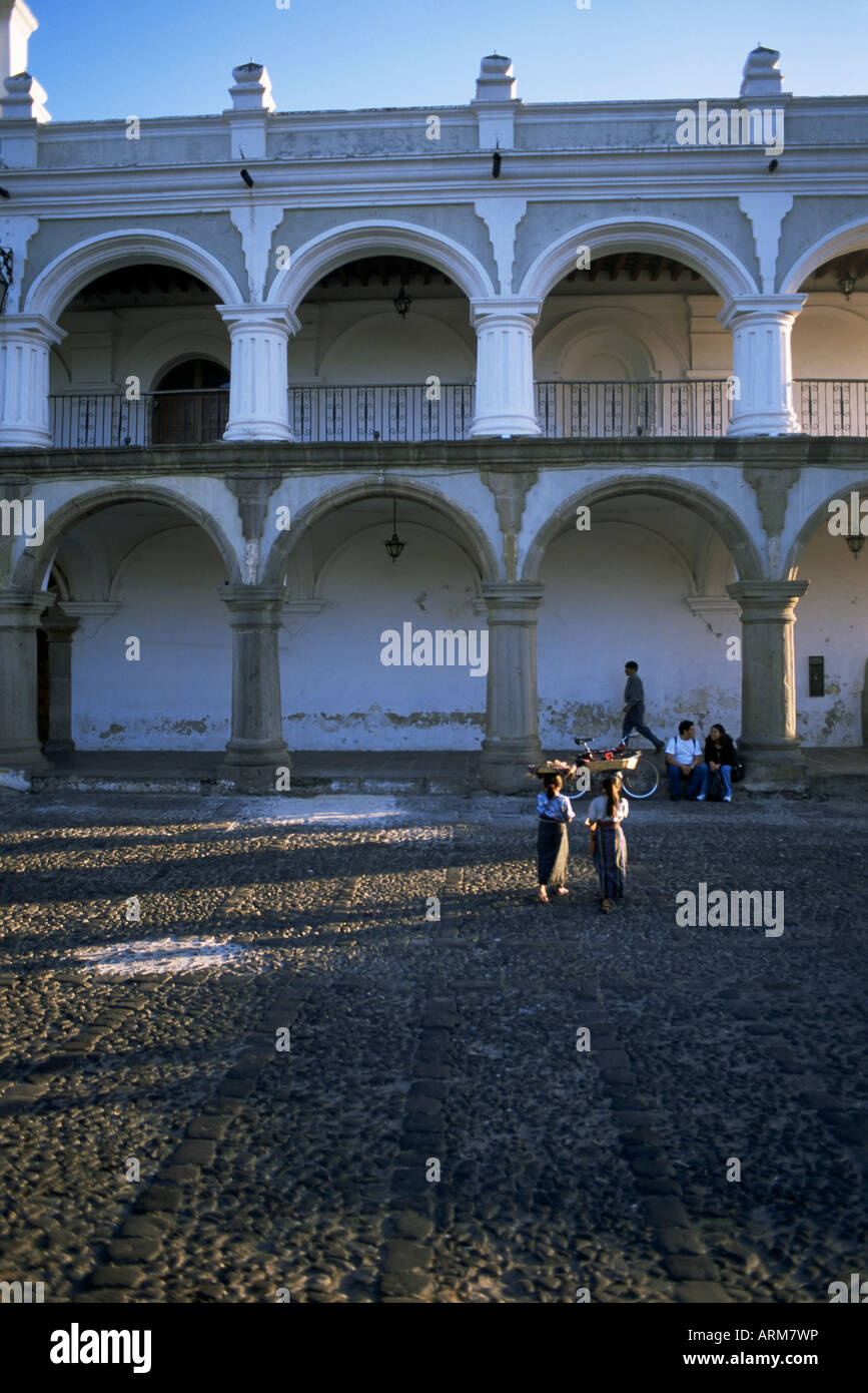 Girls in local clothing carry crafts on heads, main plaza, Antigua, Guatemala, Central America Stock Photo