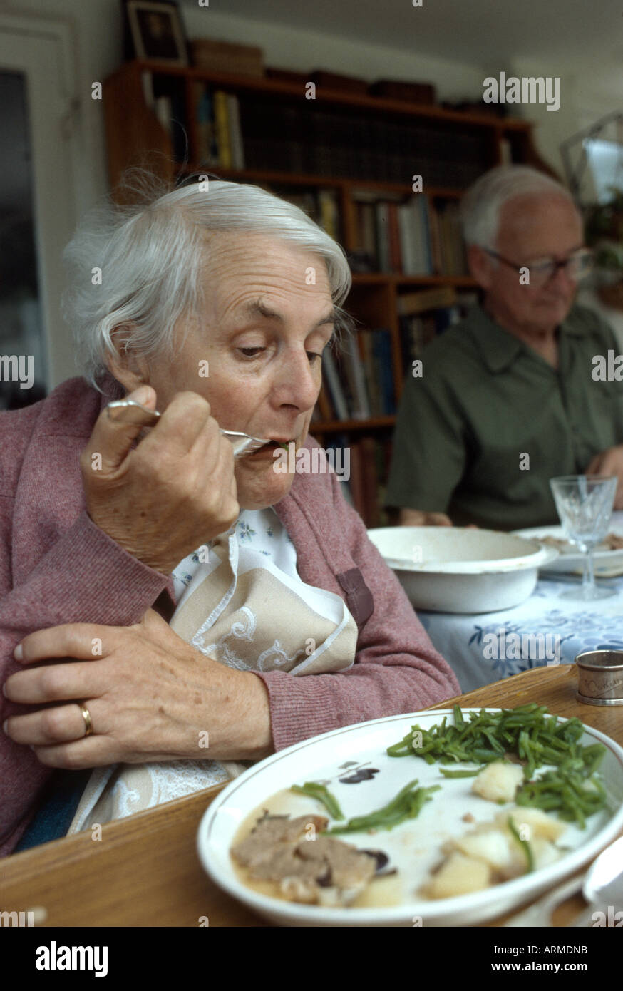 woman suffering with motor neuron disease struggles with her fork as she feeds herself Stock Photo