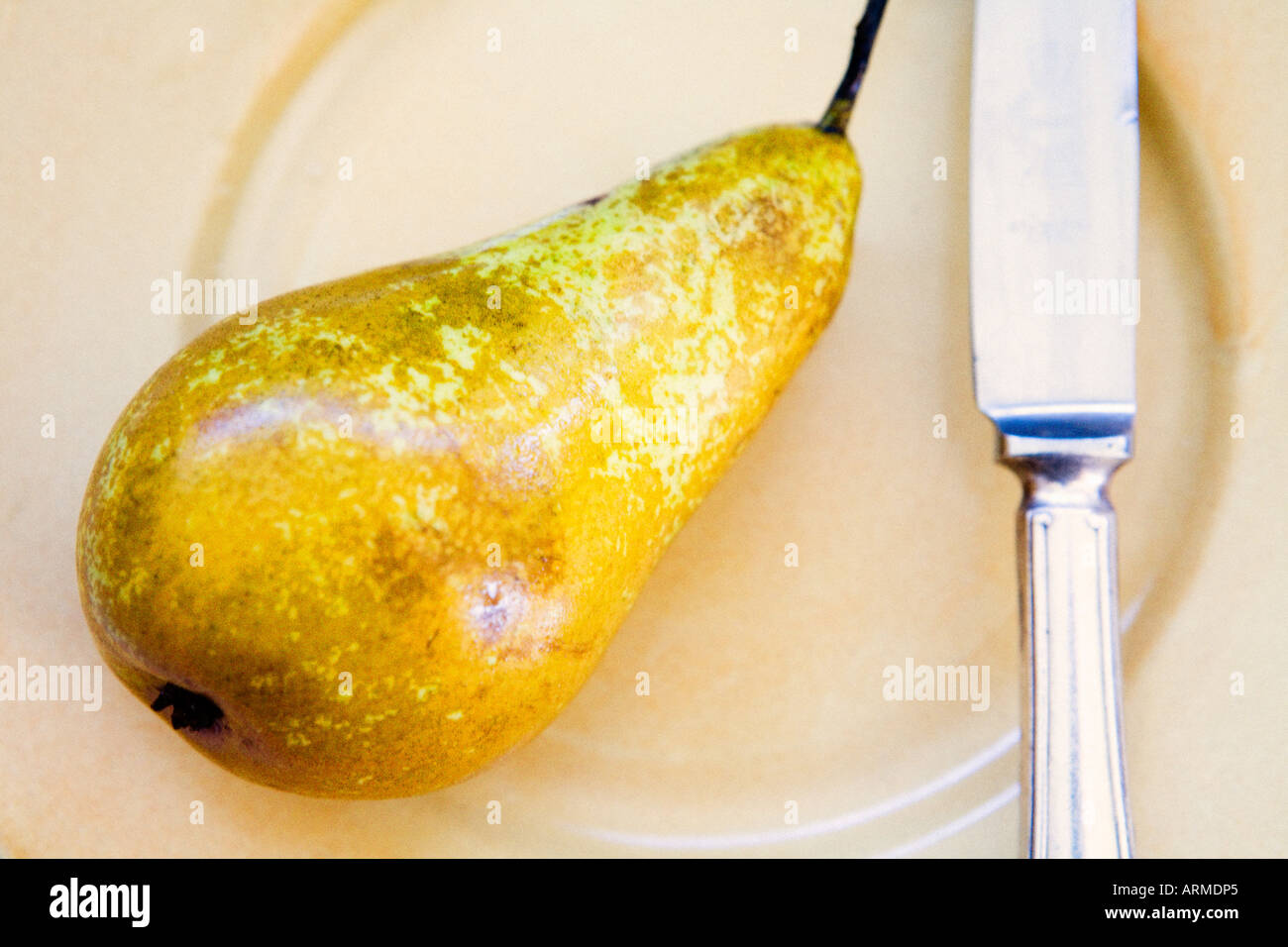 Knife and pear on plate Stock Photo