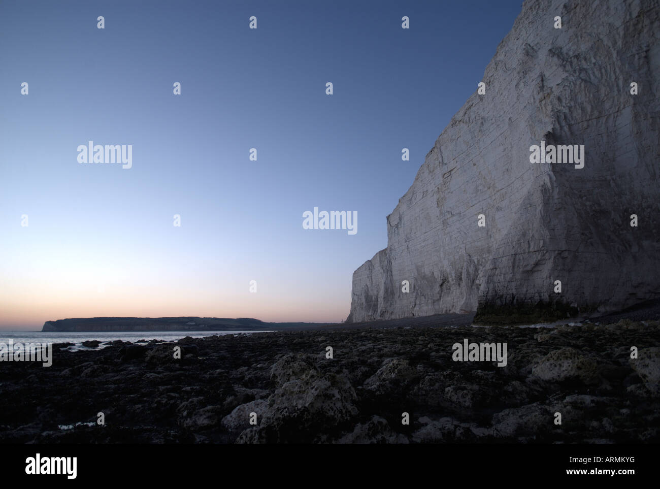 The cliff-face of the Seven Sisters cliffs at dusk with the evening blue sky behind. Stock Photo