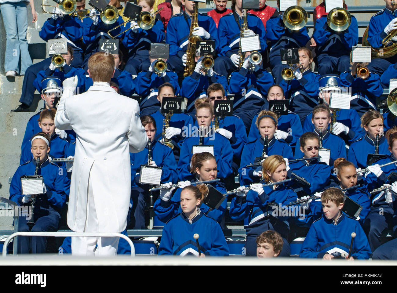 Conductor leads a High school marching band during a football game