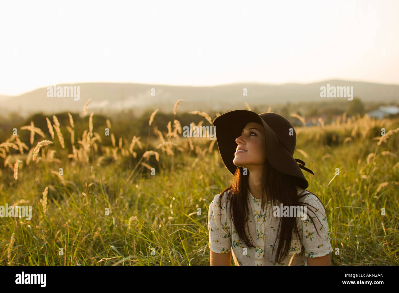 Woman wearing hat sitting in grass Stock Photo