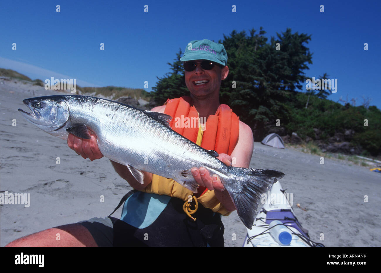 kayaker dispays fresh caught coho on Whaler Island, Clayoquot ...