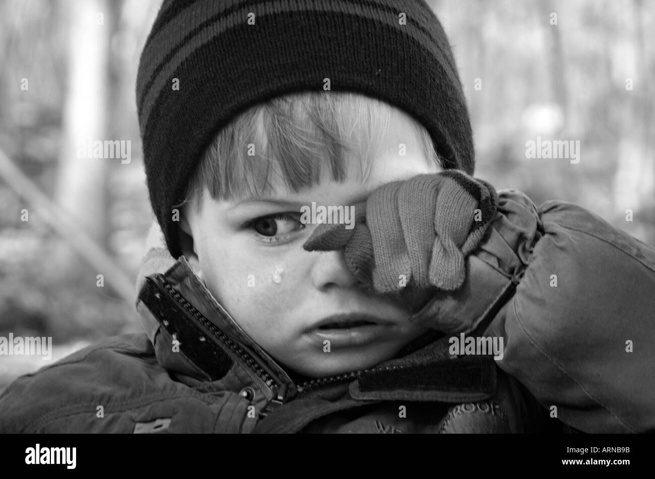 A child wipes tears from his face crying child Stock Photo