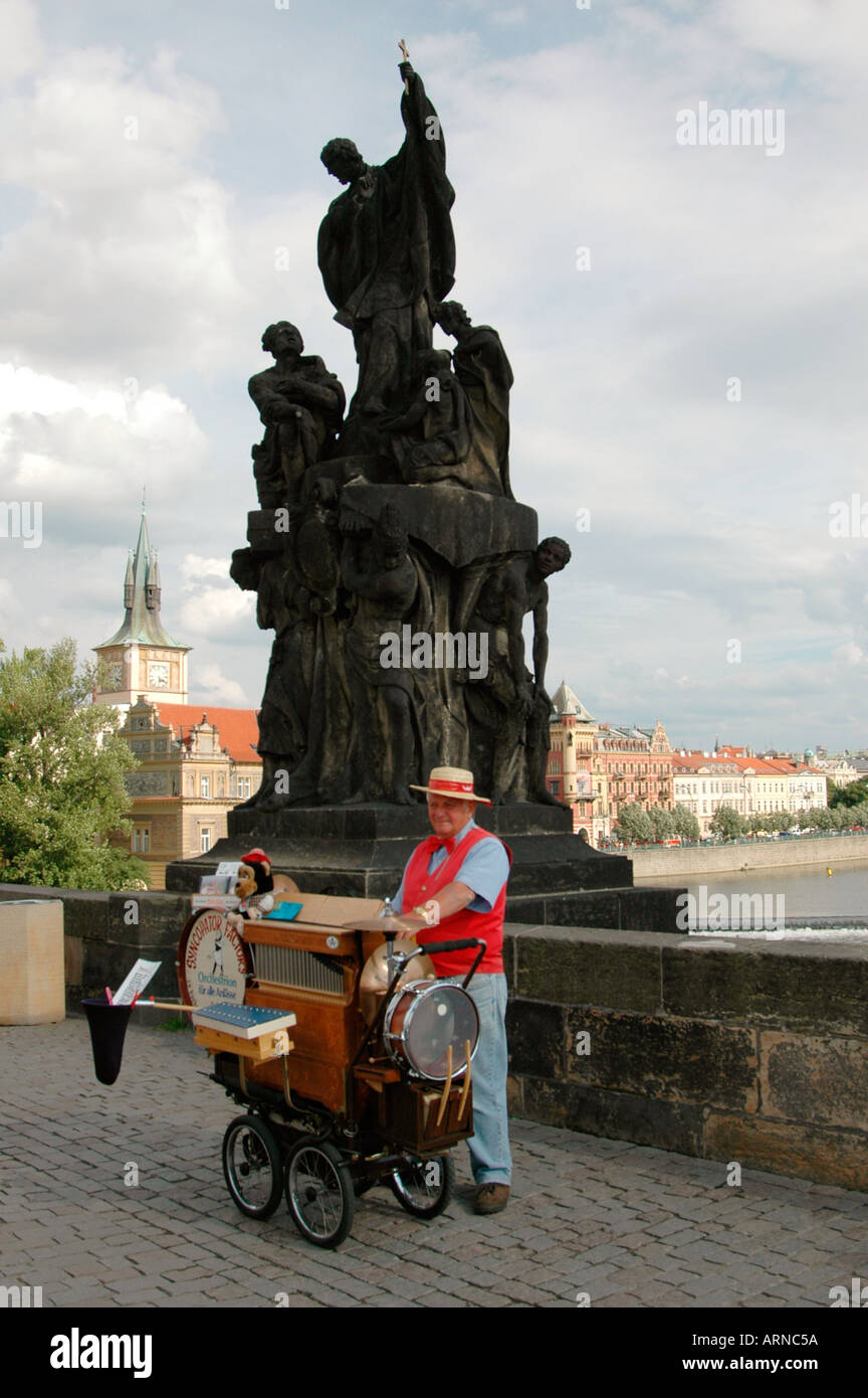 A one man band performing beneath the Statue of Francis Xavier in Charles Bridge or Karluv Most Prague Czech republic Stock Photo