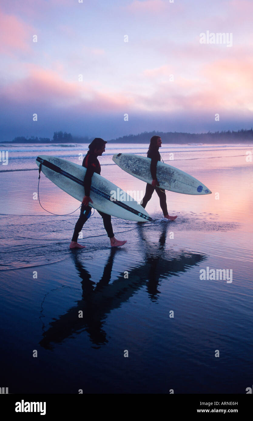 two young male surfers walking with their boards on the beach, Pacific Rim, Longbeach, Vancouver Island, British Columbia, Canad Stock Photo