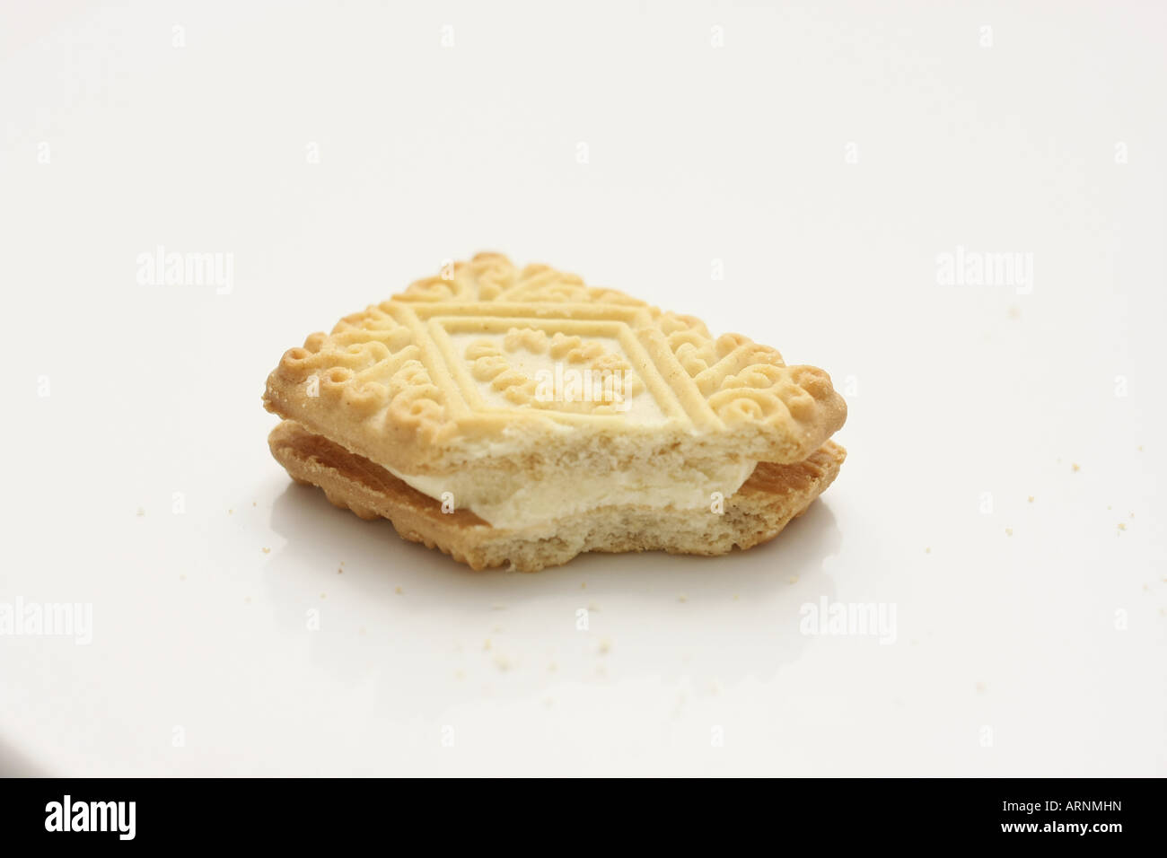 One half-eaten Custard Cream biscuit on a white plate Stock Photo