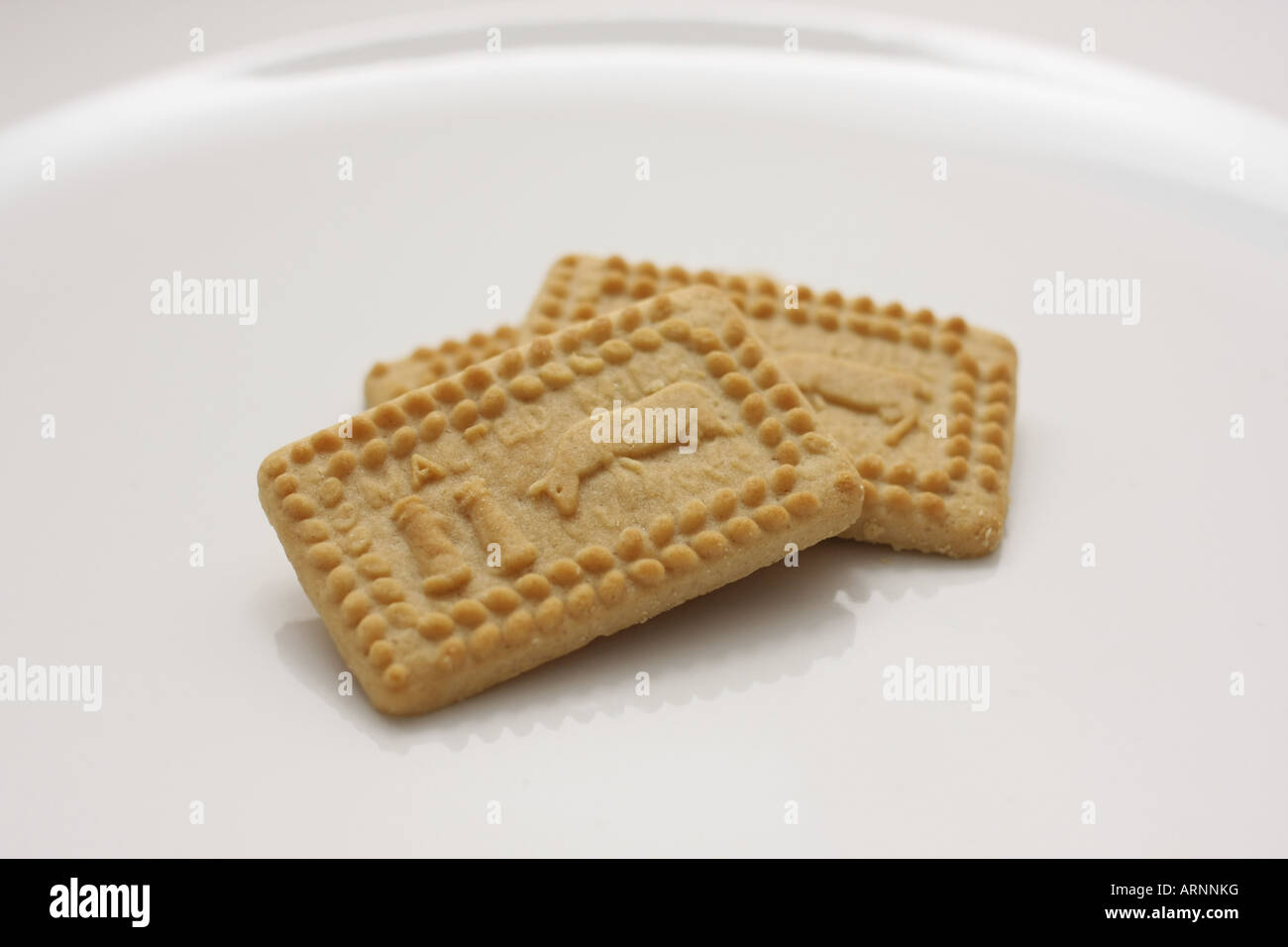 Three whole Malted Milk biscuits on a white plate Stock Photo