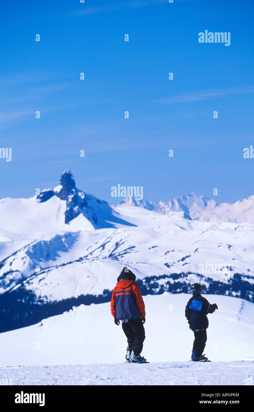 snowboarders atop peak with Garibaldi Mountain and black tusk beyond, Whistler, British Columbia, Canada. Stock Photo