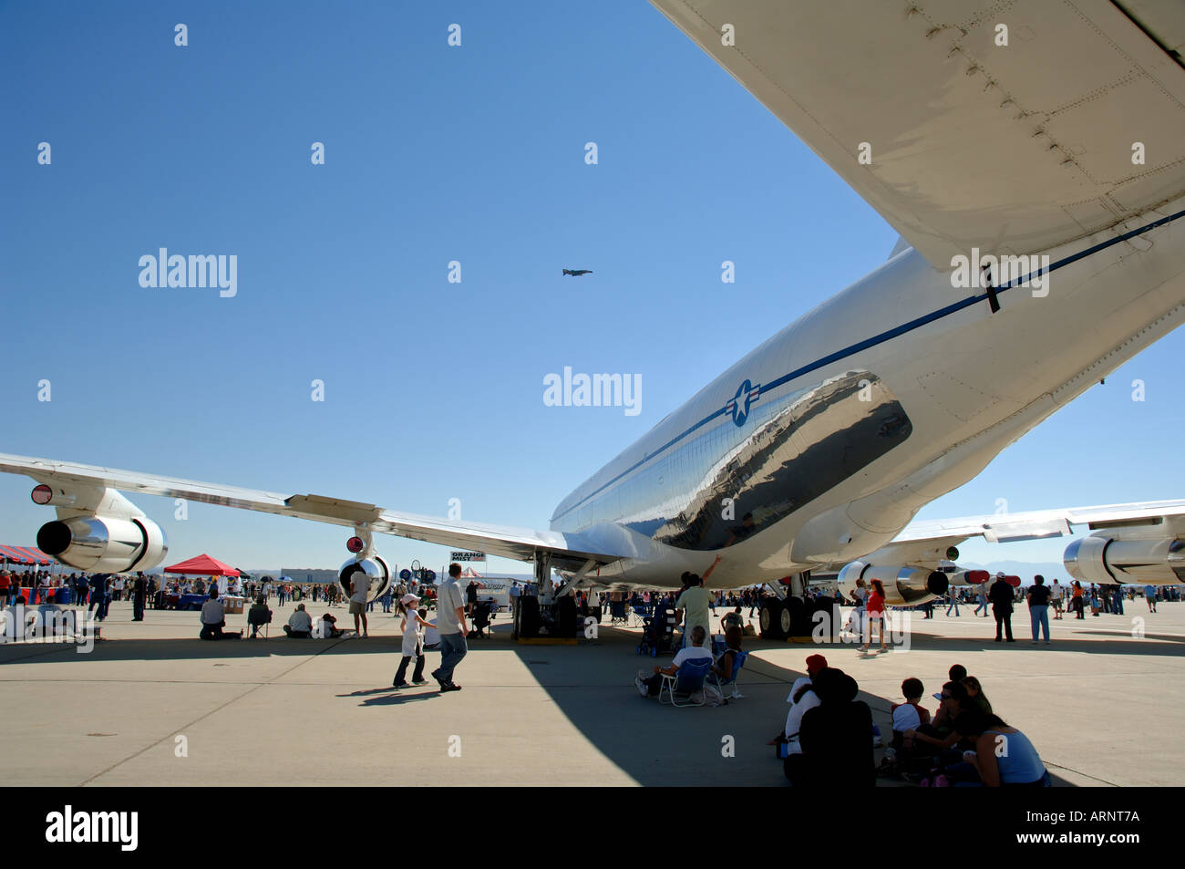 People resting under the fuselage of airplane at Edwards Air Force Base ...