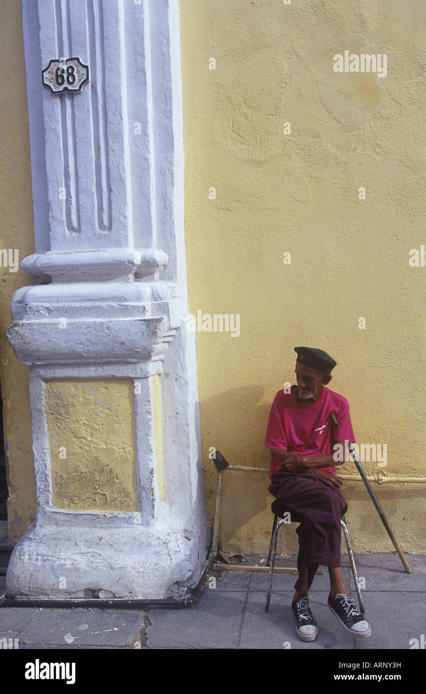 Cuba, Havana Vieja, Plaza de la Catedral area, older man rests by yellow wall Stock Photo