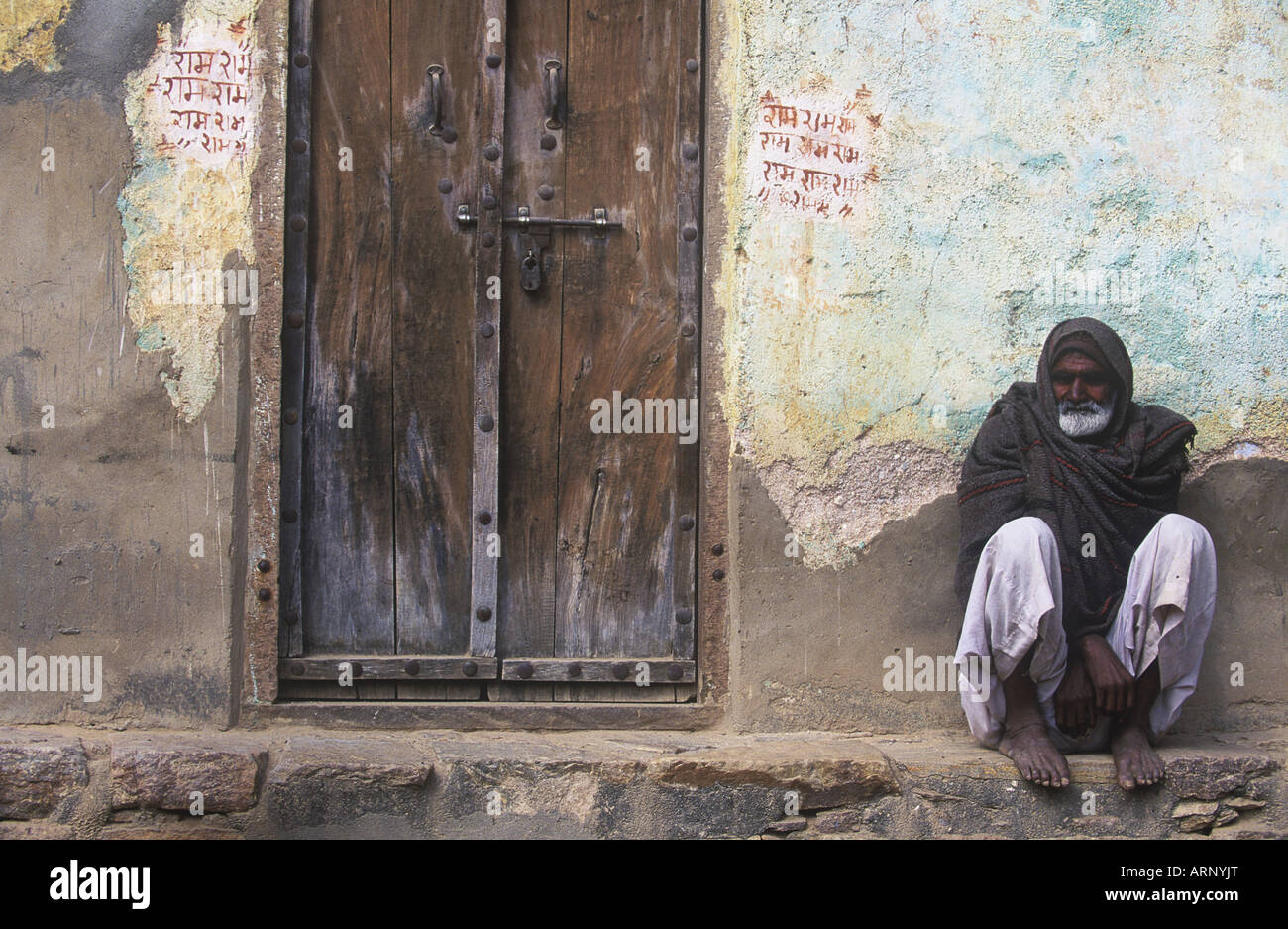 India, Rajastan, Jaipur, villager rests on ledge by door Stock Photo