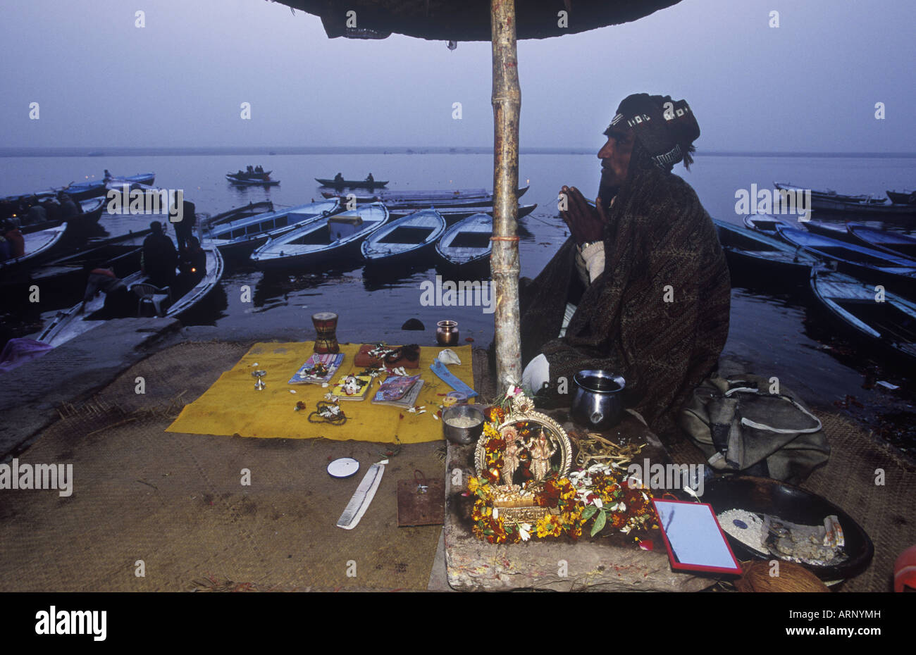 India, Varanasi, Dasaswamedh Ghat, 'priest'  prays by Ganges in morning with 'puja' paraphenalia on mat Stock Photo