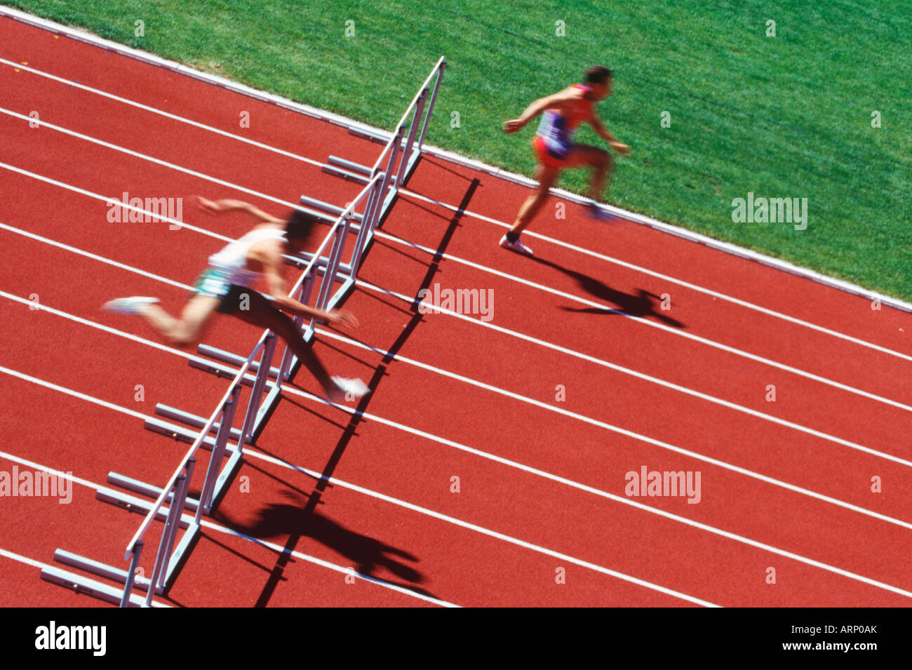 Track and field competition, hurdlers on rust coloured track Stock