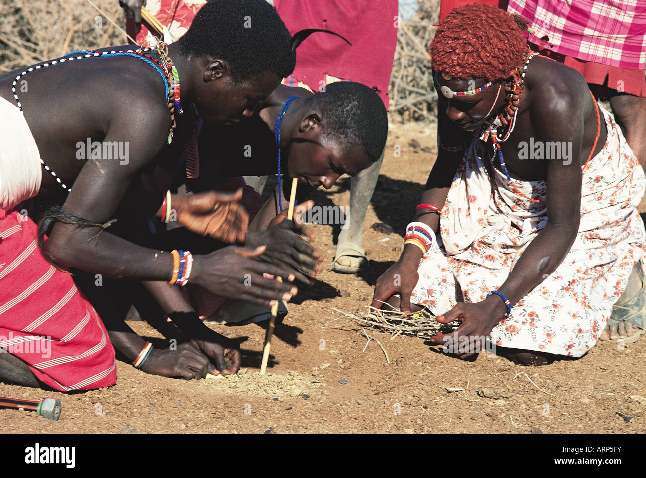 Young Samburu men making fire by rubbing two fire sticks together
