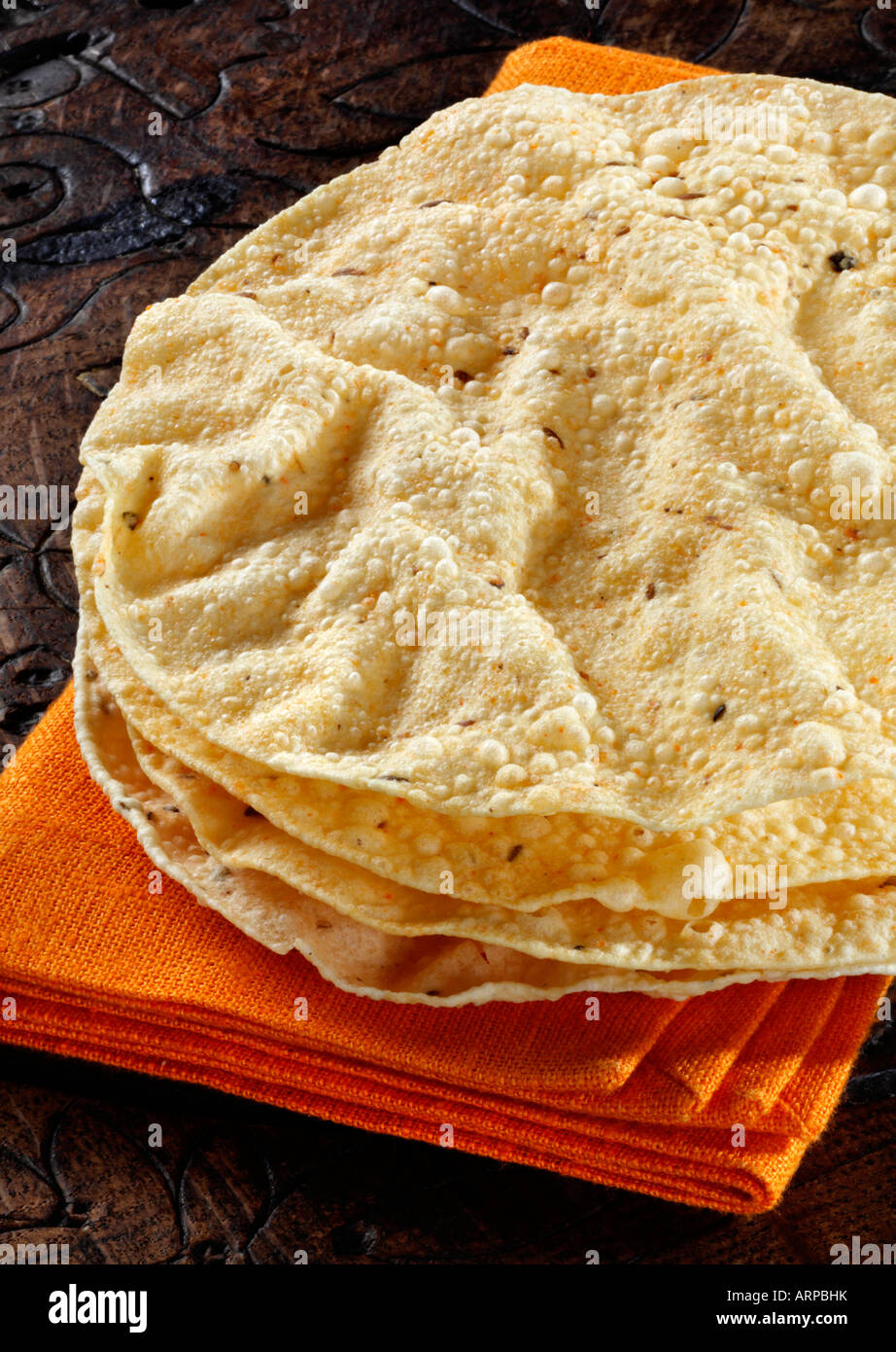 Spicy Puppodums on an orange napkin all on an ethnic wooden background. Stock Photo