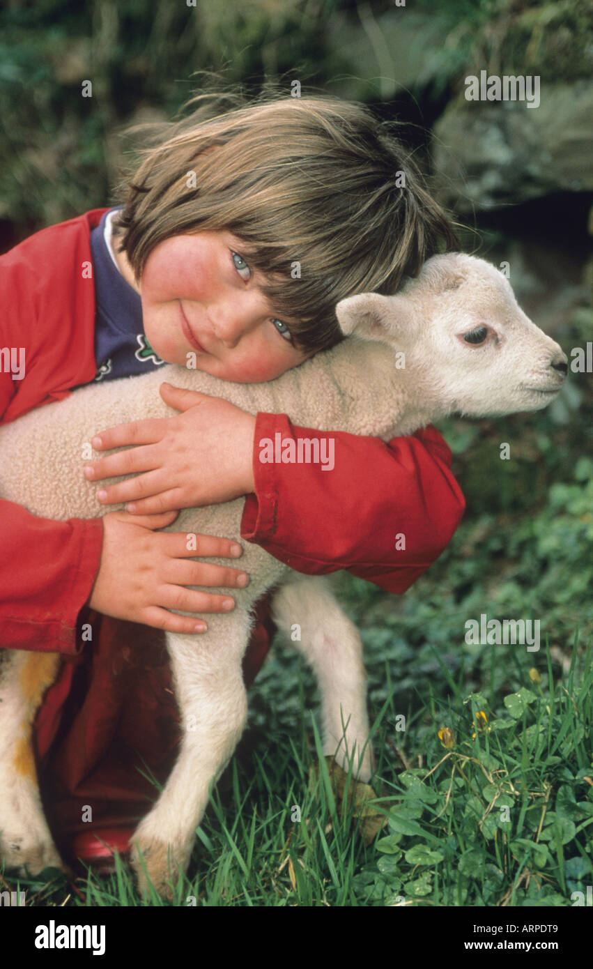 Young girl with a lamb that is being hand-reared on a Welsh farm Stock Photo