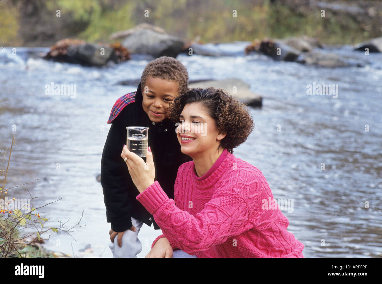Teacher and student check water sample for pollution near stream while on field trip Washington DC USA Stock Photo
