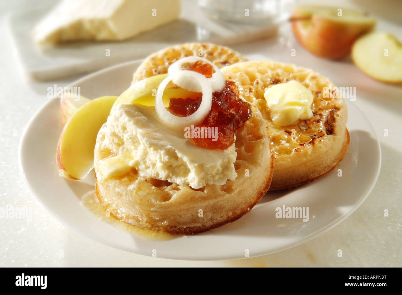 Serving of hot buttered Crumpets with wensleydale cheese and onion pickle on a white plate in a table setting Stock Photo