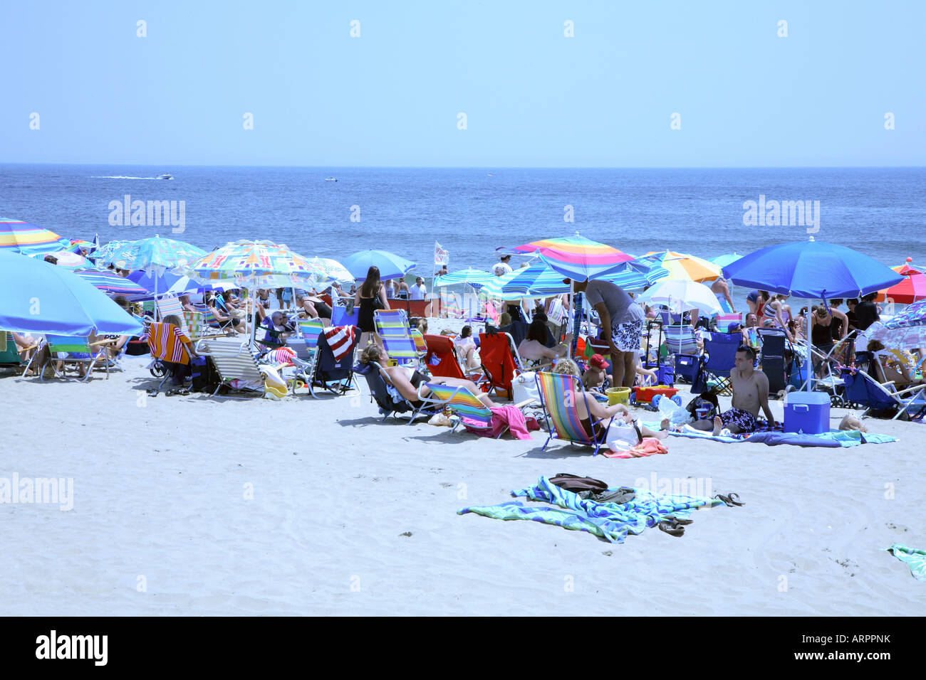 Crowd of people with colorful beach umbrellas, chairs and towels relaxing on sandy beach at New Jersey shore. Stock Photo