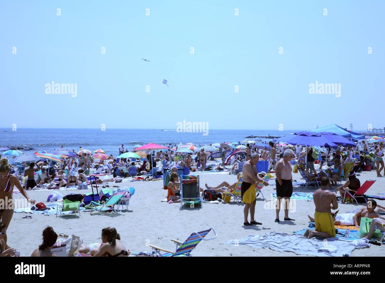Crowd of people with colorful beach umbrellas, chairs and towels on sandy beach at New Jersey shore. Stock Photo